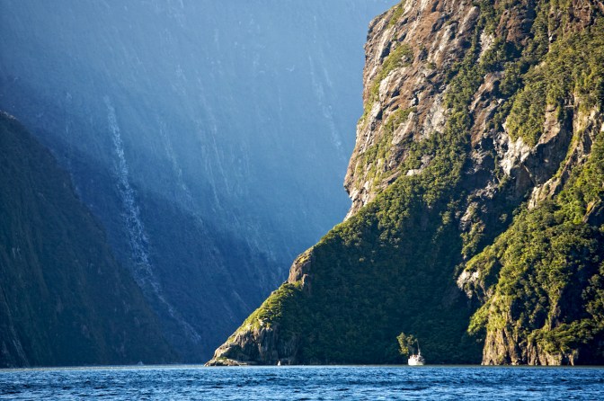 Tour boat dwarfed on Milford Sound, Fiordland Ntional Park